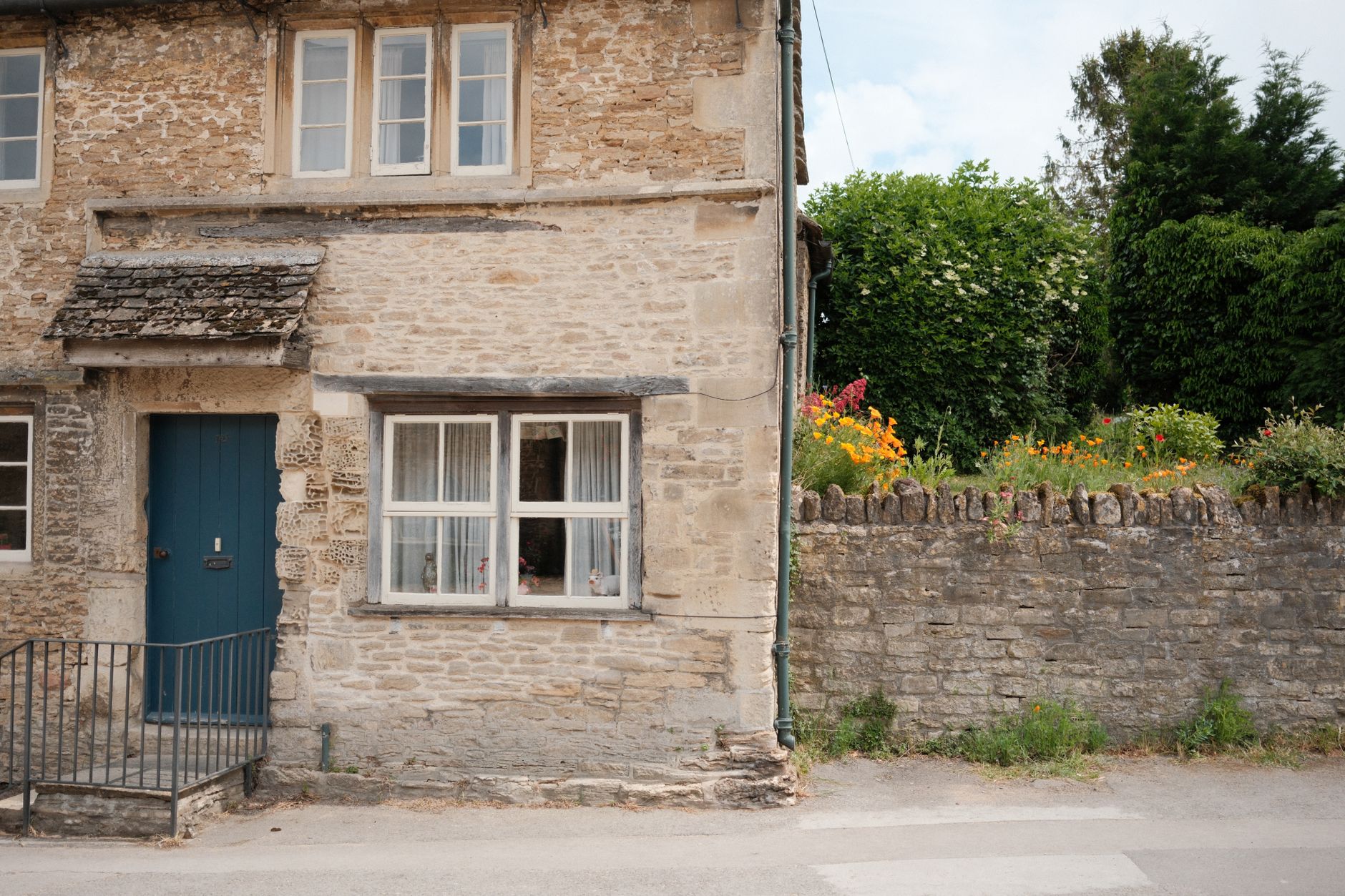 Stone cottage with a flowered wall and cottage garden