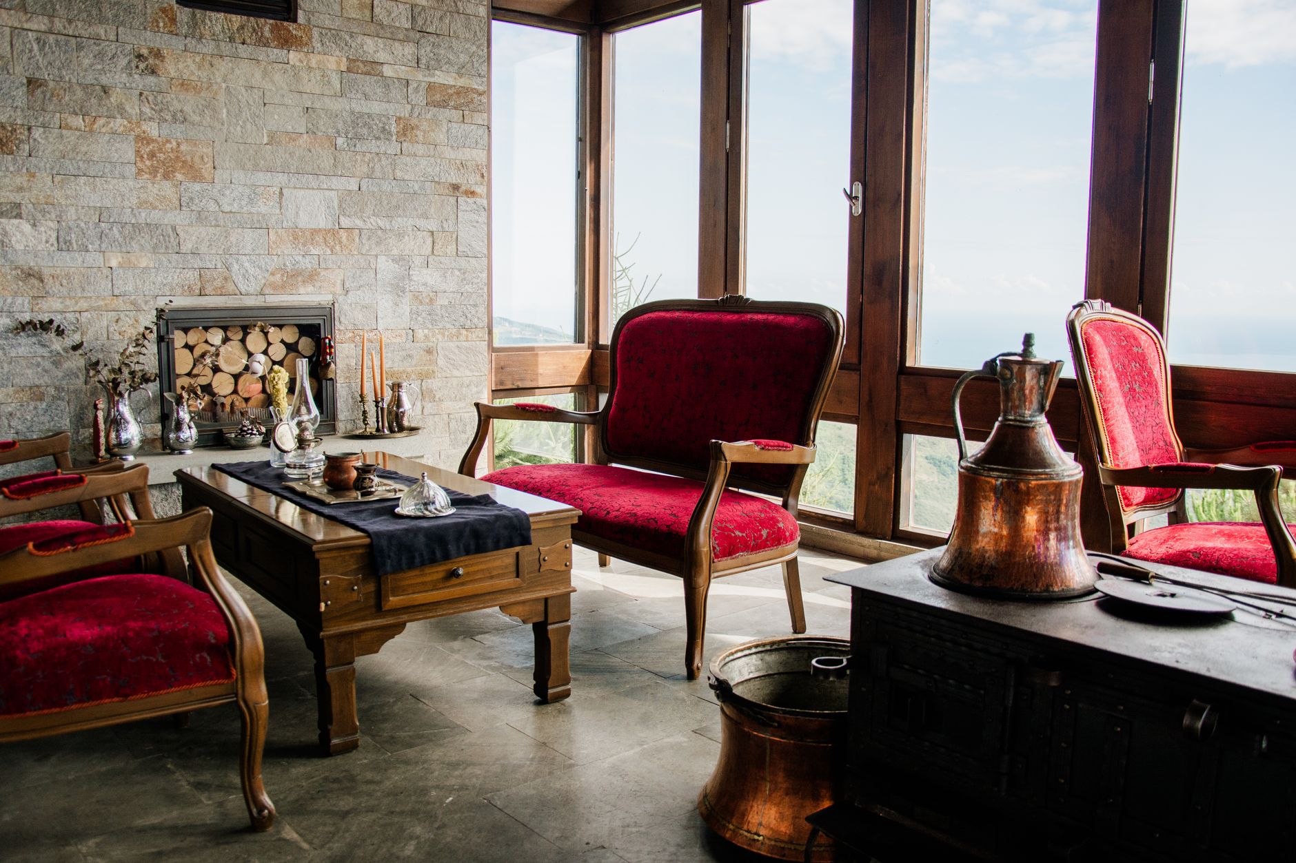 Rustic lounge with a stone fireplace, armchairs and mountain views